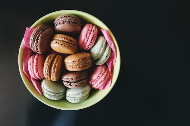 Foto grote plaat van heldere en smakelijke makarons op een zwarte achtergrond