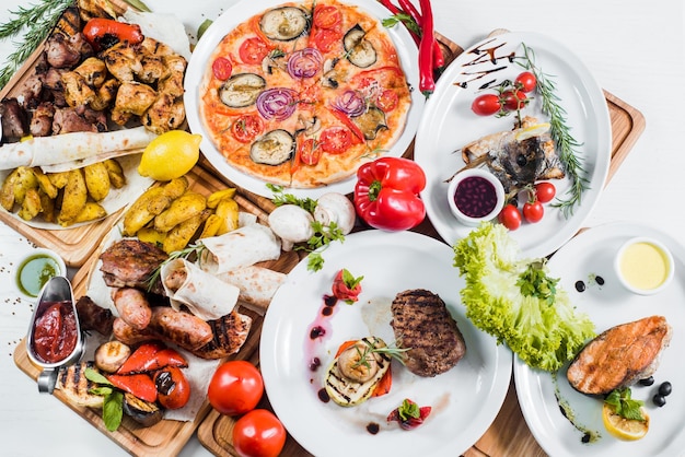 Grote reeks van verschillende gerechten met vlees, groenten, pizza en kruiden flatlay op witte achtergrond