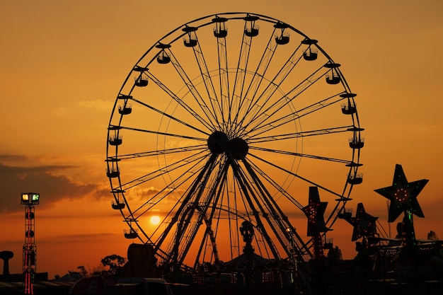 Grote reuzenradschommeling bij pretpark in silhouetzonsondergang