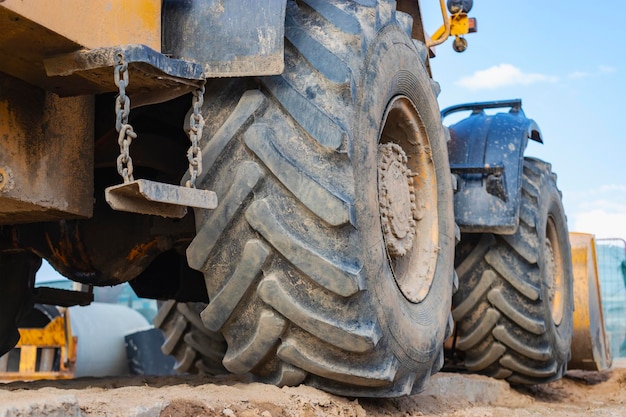 Grote rubberen wielen van grondverzet trekker auto grondverzet aan de kant van de wegenbouw Close-up van een vuil lader wiel met een groot loopvlak tegen de hemel
