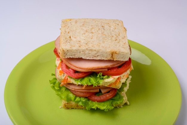 Grote sandwich met gerookte ham met sla en tomaat op groene plaat Fastfood