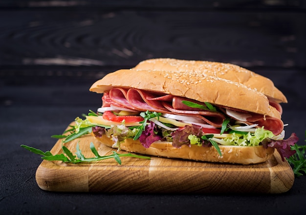 Grote sandwich met ham, salami, tomaat, komkommer en kruiden