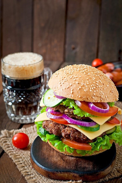 Grote sappige hamburger met groenten en rundvlees op een houten achtergrond in rustieke stijl