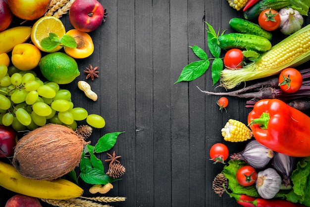 Grote selectie van rauwe groenten en fruit op een zwarte houten tafel Vrije ruimte voor uw tekst Bovenaanzicht