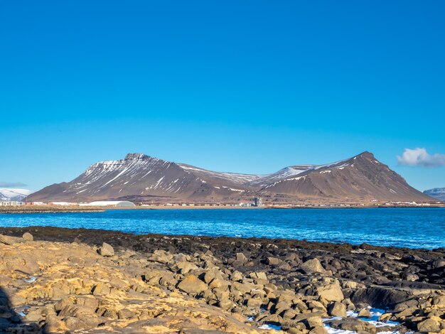 Grote stenen bij Akranes-schiereiland dichtbij de vuurtorens onder blauwe hemel IJsland