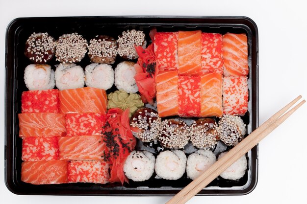 Grote sushi set ib zwarte plastic doos op wit, bovenaanzicht close-up, kopieer ruimte