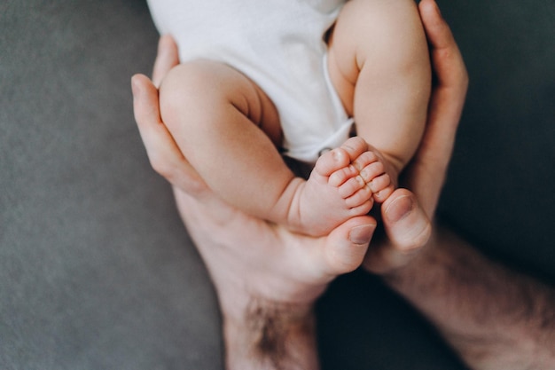 Grote vaders handen met kleine babyvoeten. Pasgeboren baby fotoshoot idee. Baby voeten close-up foto