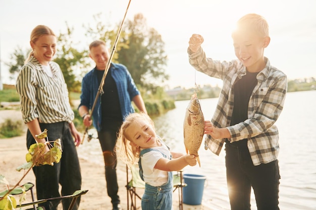 Foto grote vangst vader en moeder met zoon en dochter op samen buiten vissen in de zomer