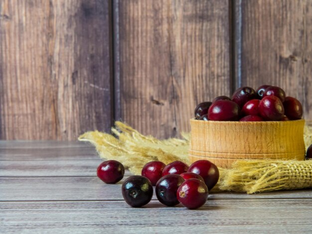 Grote veenbessen in een houten kom op een houten ondergrond. Gezonde voeding en voeding. Plaats voor tekst.