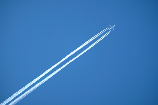 Grote viermotorige supersonische passagiersvliegtuigen vliegen van links naar rechts hoog in helderblauwe wolken