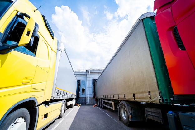 Foto grote vrachtwagens in de buurt van magazijn tegen blauwe hemelachtergrond