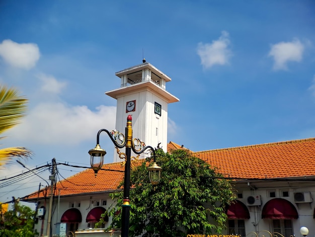 Grote wandklok in een oud wit gebouw in madiun, oost-java, indonesië met een prachtige helderblauwe lucht