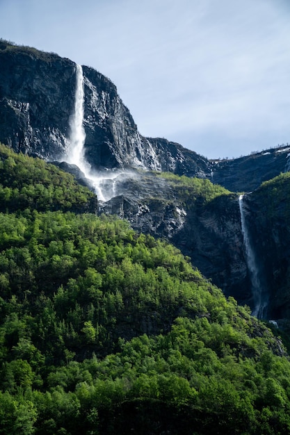 Grote waterval die oprijst in de bergen, omringd door groene bomen in Noorwegen