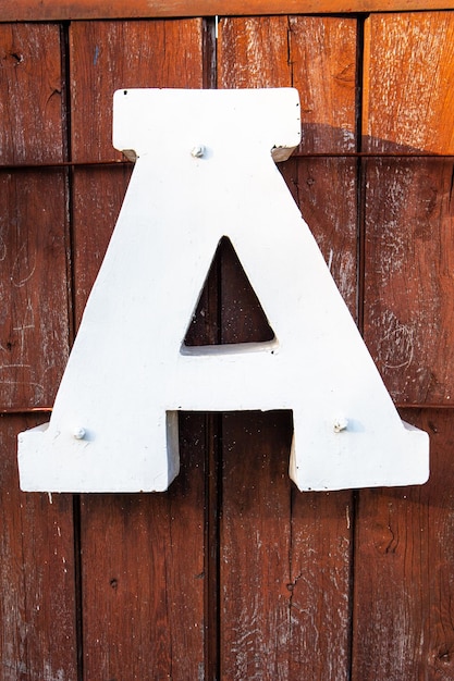 Grote witte letter a op een donkere houten achtergrond verlicht door de zon