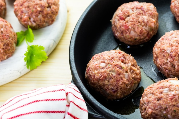 Foto grote zelfgemaakte italiaanse gehaktballen bakken op een middelgrote koekenpan voor het avondeten.