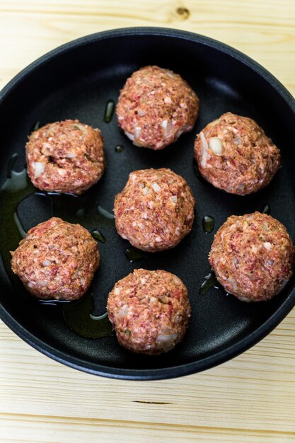 Grote zelfgemaakte Italiaanse gehaktballen bakken op een middelgrote koekenpan voor het avondeten.