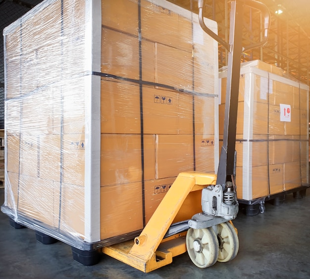 Grote zending palletgoederen en gele handpallettruck. Cargo export & Shipping magazijn,