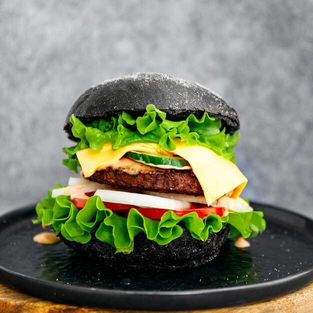 Grote zwarte burger met marmeren runderpasteitjes en verse groenten