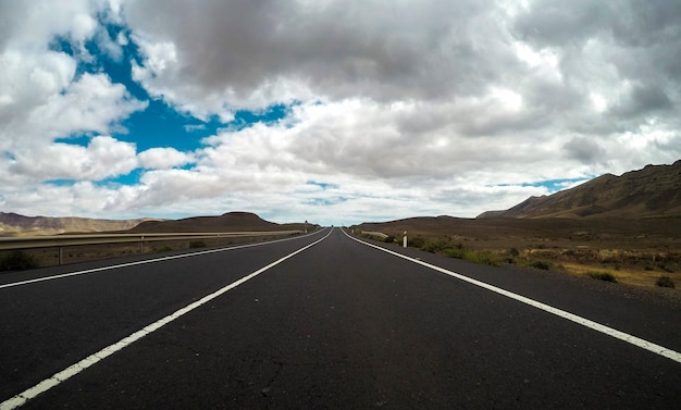 長い道のりのまっすぐなアスファルト道路と青い雲の空の地面の美しい景色