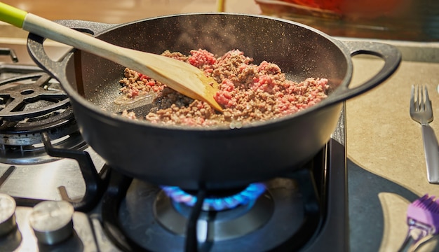 Говяжий фарш жарят на сковороде для спагетти болоньезе по рецепту из интернета.
