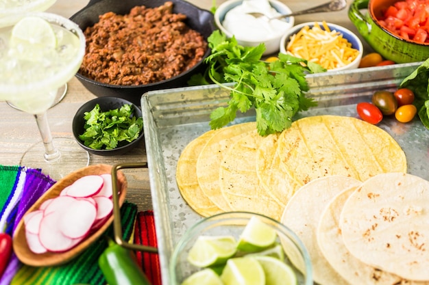 Tacos di carne macinata con lattuga romana, pomodori a dadini, ravanelli e formaggio cheddar grattugiato.
