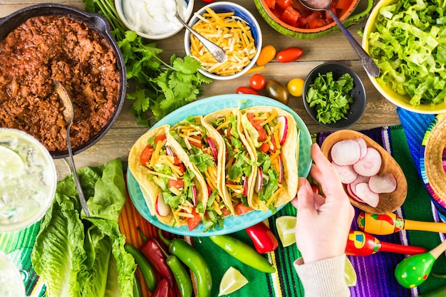 Ground beef tacos with romaine lettuce, diced tomatoes, radished, and shredded cheddar cheese.