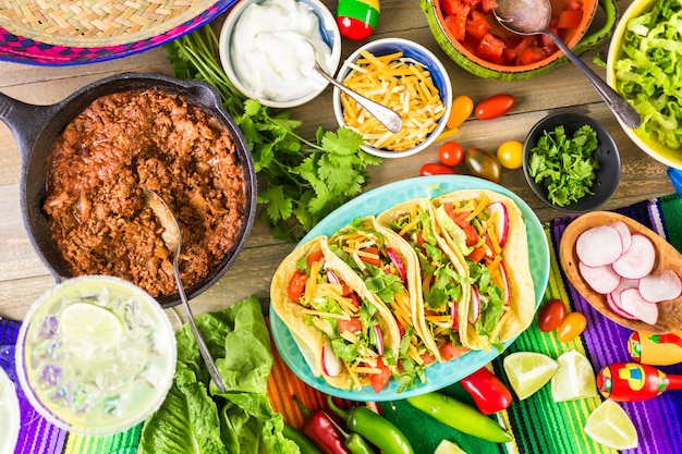 Tacos di carne macinata con lattuga romana, pomodori a dadini, ravanelli e formaggio cheddar grattugiato.