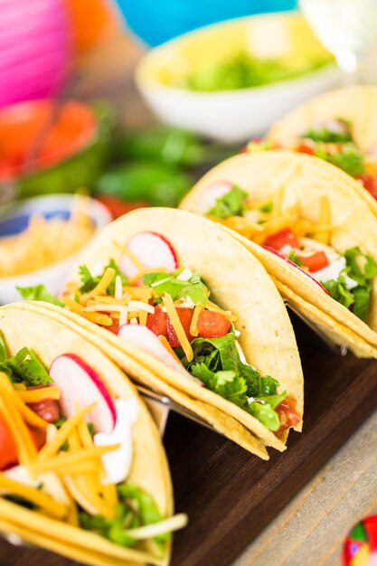 Ground beef tacos with romaine lettuce, diced tomatoes,\
radished, and shredded cheddar cheese.