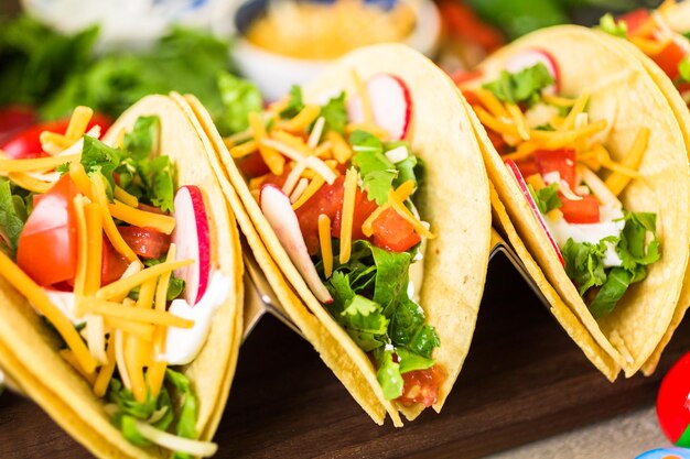 Ground beef tacos with romaine lettuce, diced tomatoes,\
radished, and shredded cheddar cheese.