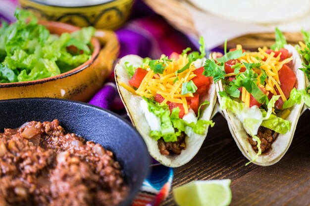 Ground beef tacos with romaine lettuce, diced tomatoes, and\
shredded cheddar cheese.