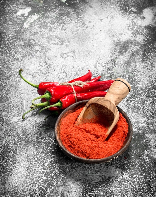 Ground chili peppers in a bowl on a rustic background