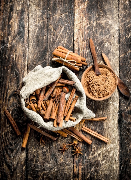 Ground cinnamon in bowl with cinnamon sticks in a bag.