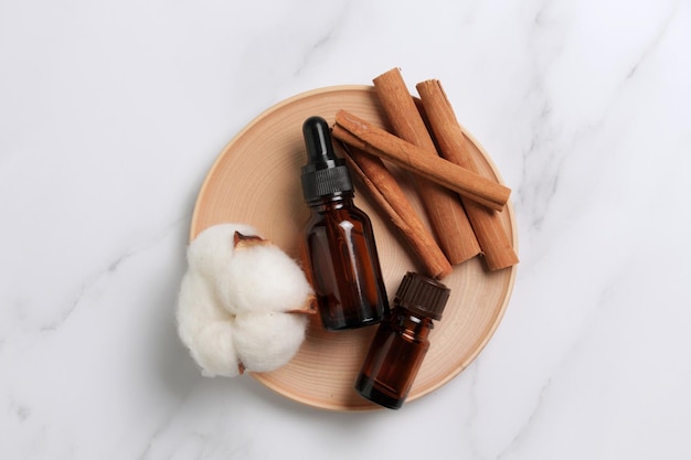 Ground cinnamon essential oil and cinnamon sticks cinnamon on a marble background