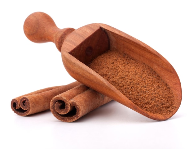 Ground cinnamon spice powder in wooden spoon isolated on white background cutout