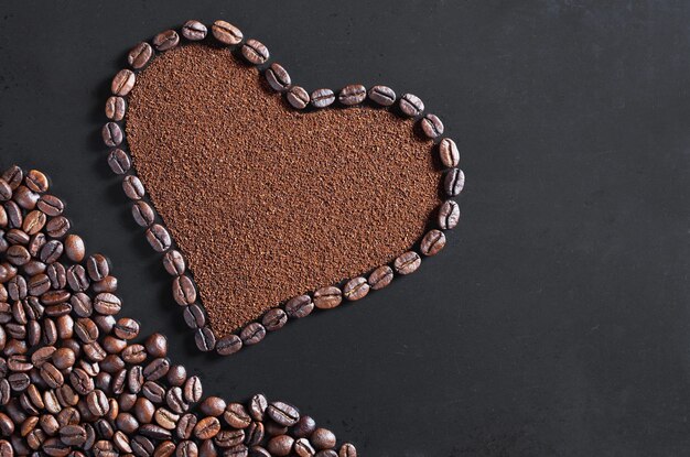 Ground coffee and beans in the shape of a heart on old black metal background, top view with place for text