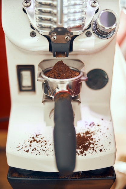 Foto caffè macinato versato in un portafiltro con macinino.