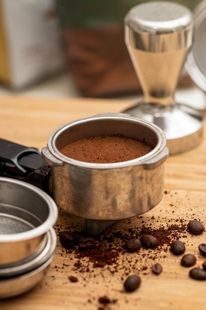 Ground and compressed coffee in the filter holder with coffee beans scattered around