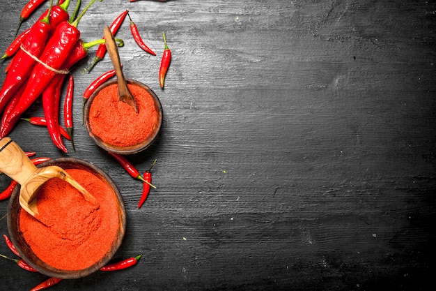 Ground hot peppers in a wooden bowl. On the black chalkboard.