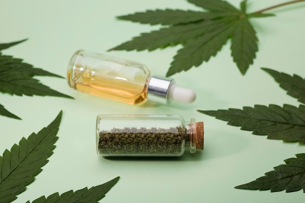 ground marijuana bite in glass jar marijuana oil in drops dispenser bottle and green leaves green