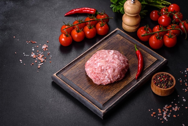 Ground meat with ingredients for cooking on black background