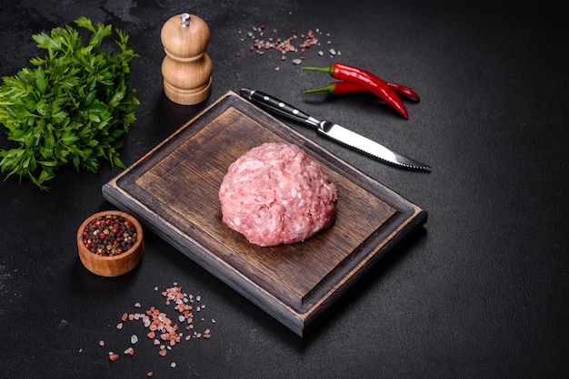 Ground meat with ingredients for cooking on black background