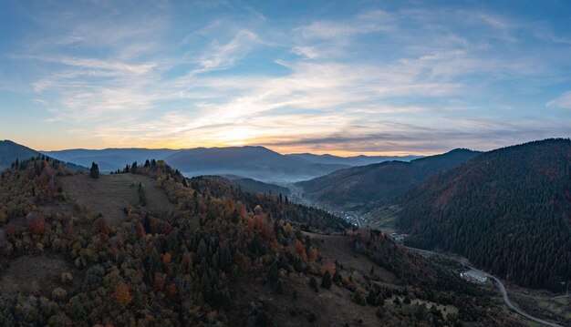 Ground road in high mountains with green forest at sunrise