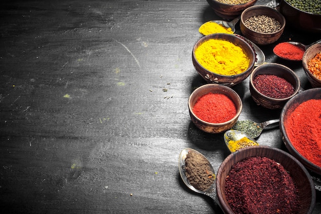 Ground spices in bowls and spoons. On the black chalkboard