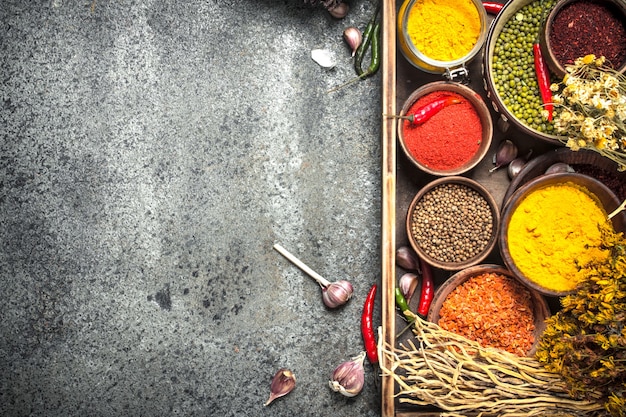 Ground spices in bowls on wooden tray on rustic table.