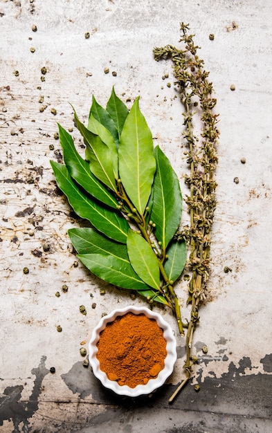 Foto spezie macinate con foglie di alloro ed erbe aromatiche.