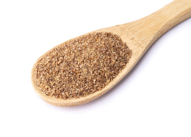 Ground whole wheat on a spoon isolated over white background.