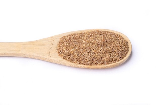 Ground whole wheat on a spoon isolated over white background