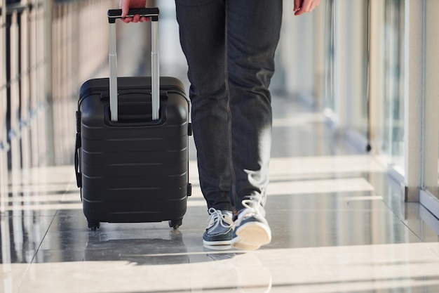 写真 エレガントなフォーマルな服を着た男性の乗客の地上の景色は、荷物を持って歩いている空港ホールにあります。