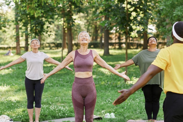 Group of active senior women enjoying yoga outdoors