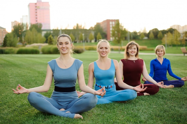A group of adult women attending yoga outside in the park